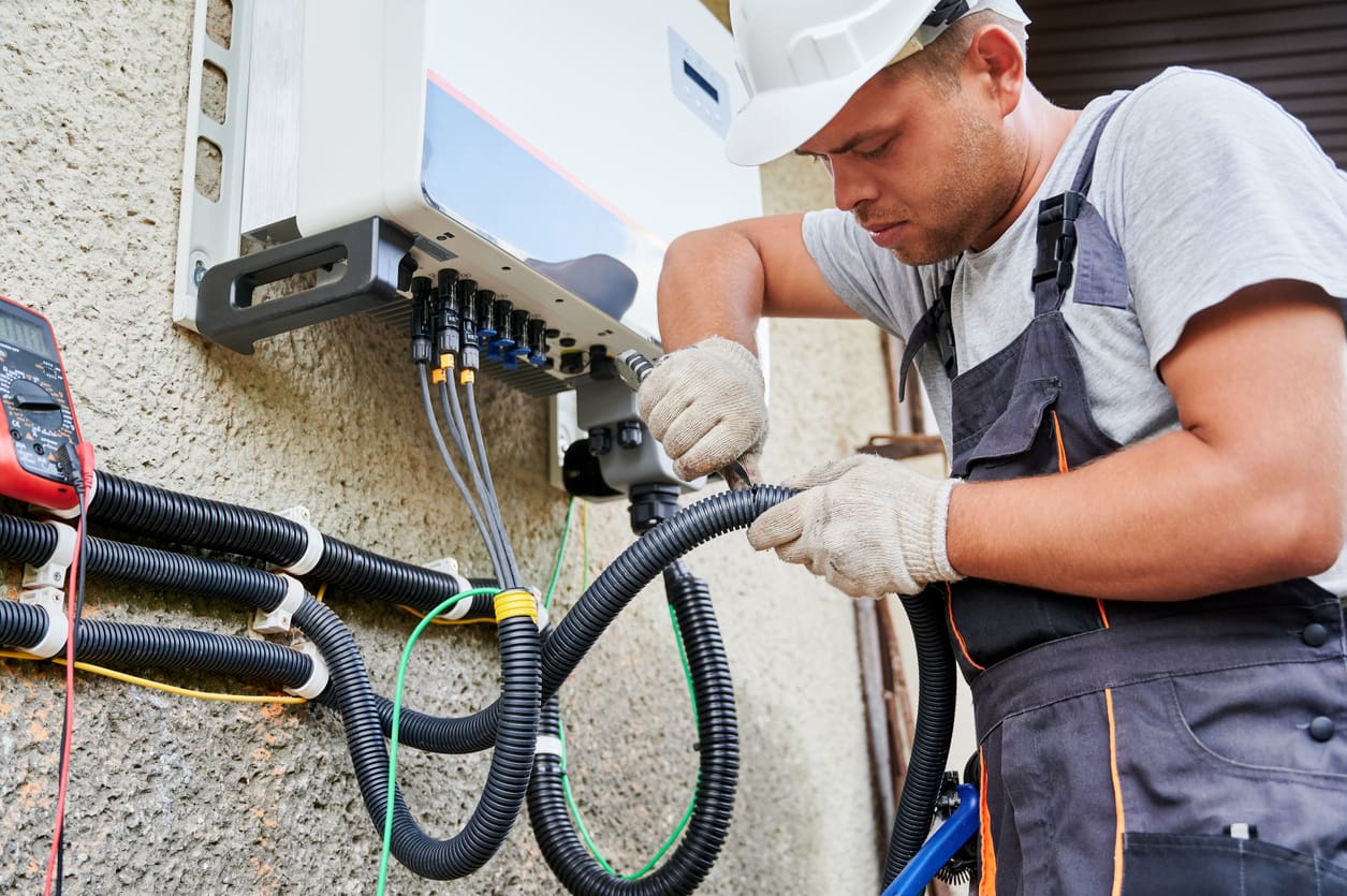 Electrician installing solar panel system, wiring inverter and electric box