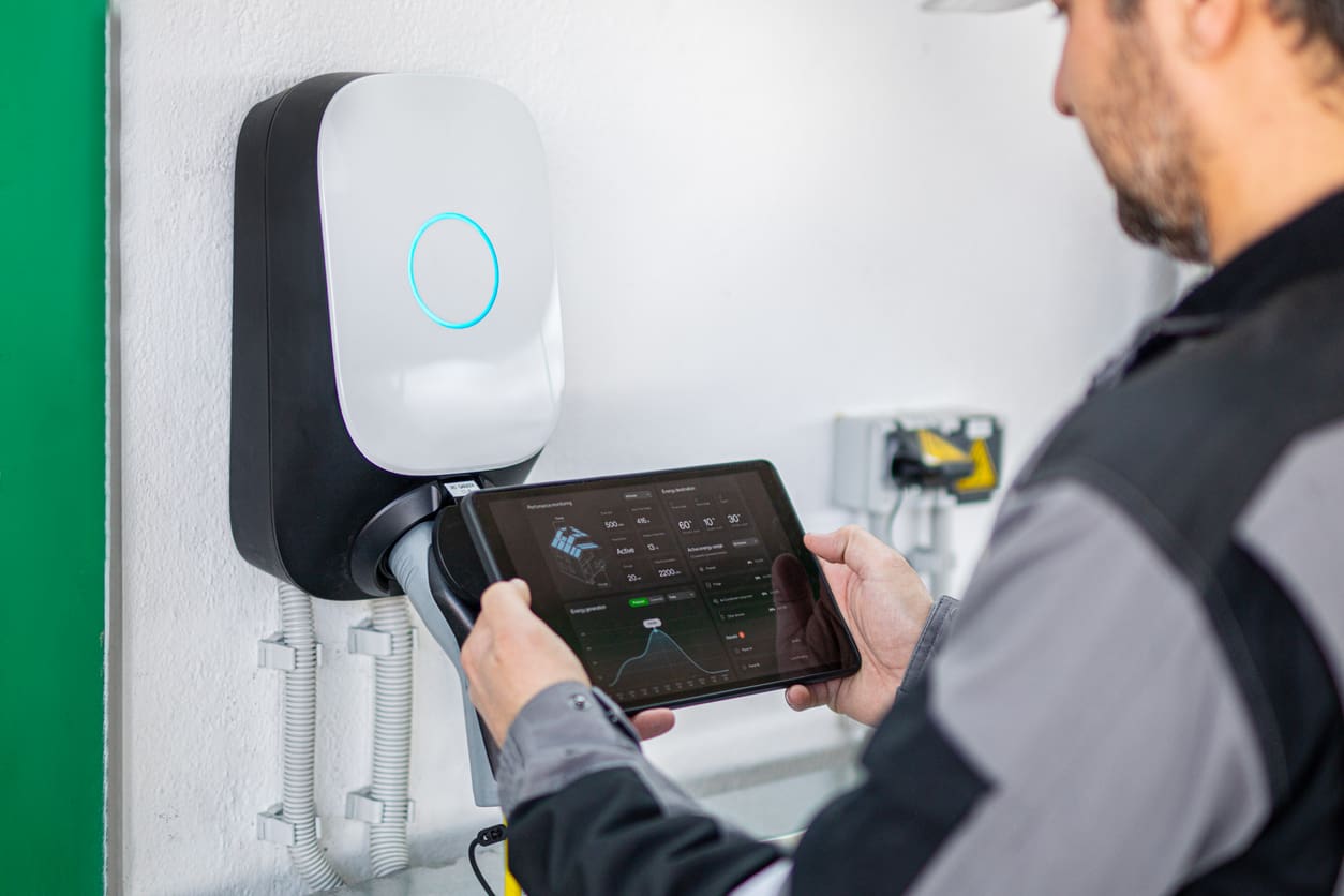 Engineer using a digital tablet to examine electric car charging station